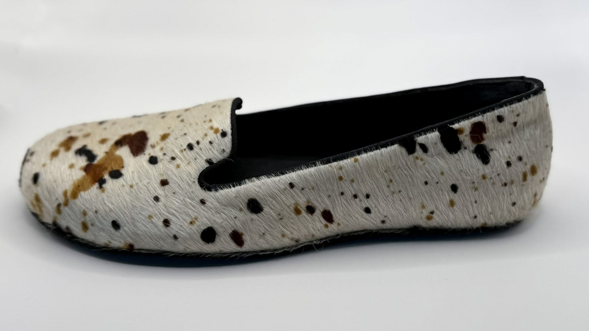 White flat shoe with brown speckles on a white background